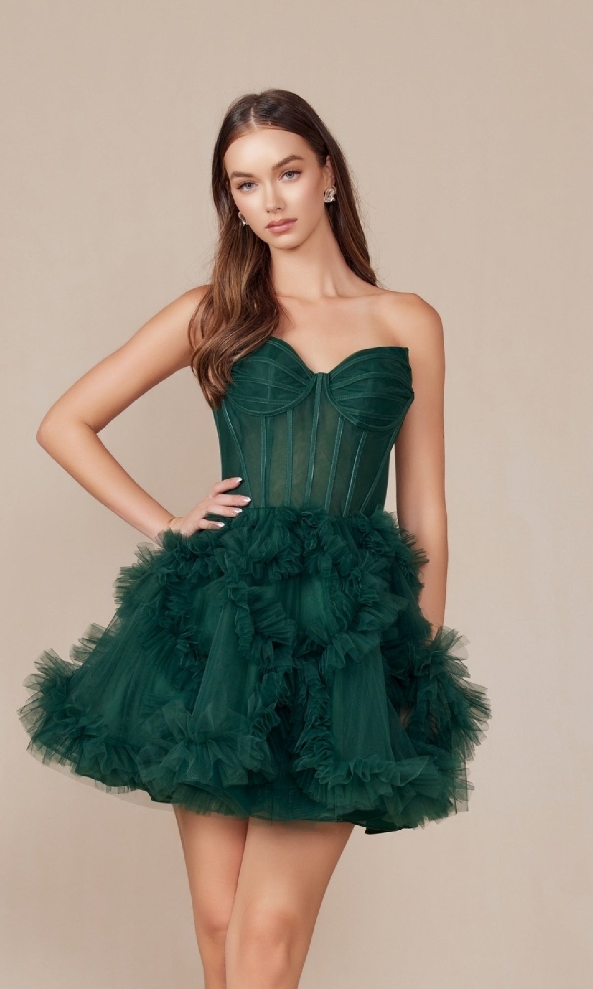 A woman models the Short Strapless Ruffled Homecoming Dress Y859 in dark green tulle, featuring a fitted bodice and ruffled skirt, standing against a plain beige background.